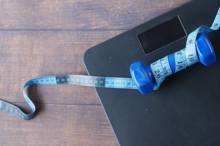 Fitness concept with dumbbell and weight scale on black