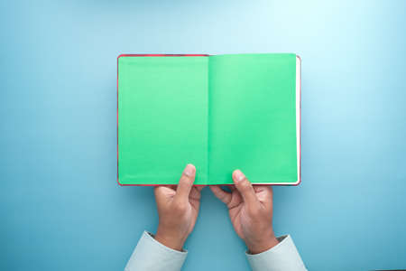 high angle view of holding open notepad on blue backgroundの写真素材