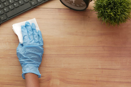 hand in blue rubber gloves holding spray bottle cleaning table