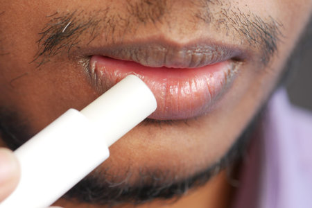young man applying moisturising lip balm on lips.