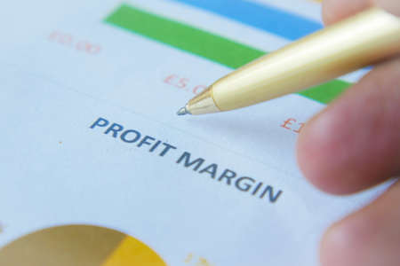 man hand with pen analyzing bar chart on paperの写真素材