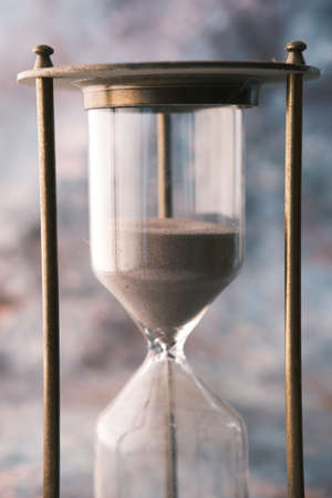 hourglass on table, sand flowing through the bulb of sandglassの写真素材