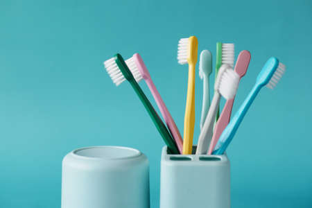 colorful toothbrushes in white mug against light green backgroundの写真素材