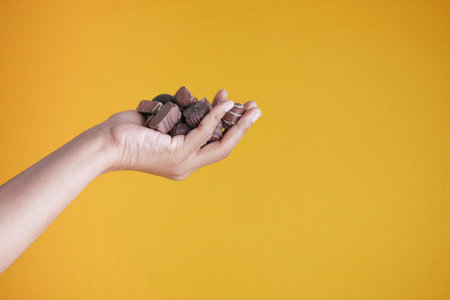 holding dark chocolate on yellow background