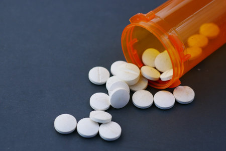 white color medical pills spilling on black background