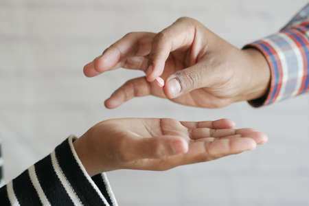 Close up of man hand holding pills and giving it to other personの写真素材