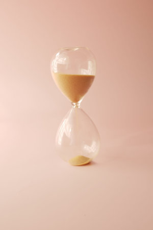 hourglass on table, sand flowing through the bulb of sandglass