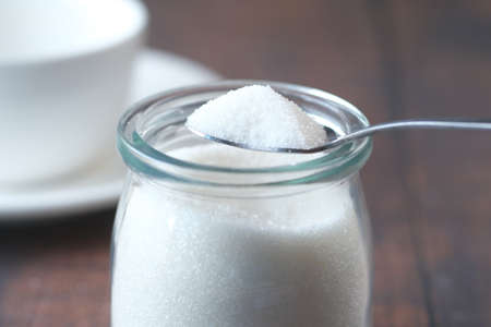 white sugar and spoon in a container on black background,の写真素材