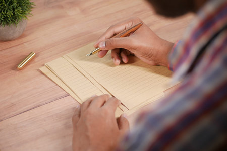 rear view of young man writing with a fountain pen on a vintage paperの写真素材