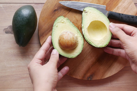 women hand cutting slice of avocado with knife,