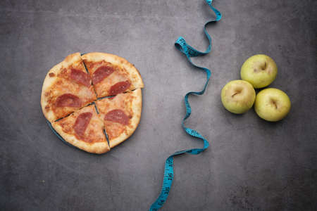 measuring tape, a green apple and pizza on black backgroundの写真素材