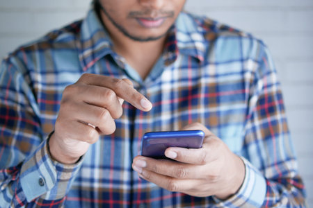Close up of young man hand using smart phone.
