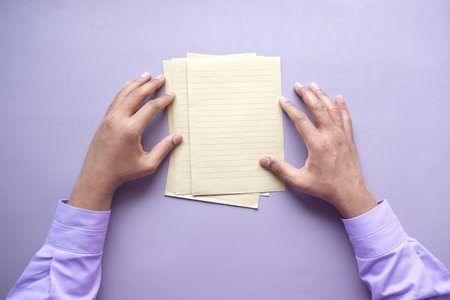 top view of mens hand on blank paper on table