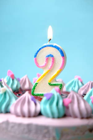 slow motion of burning candle on a birthday cake on light green backgroundの写真素材