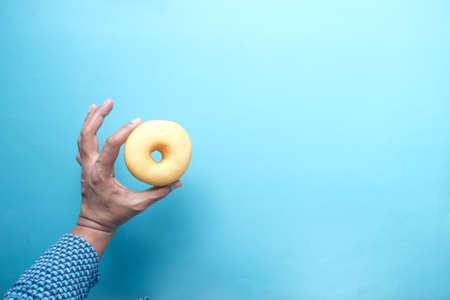 hand holding fresh donuts on light green background top viewの写真素材