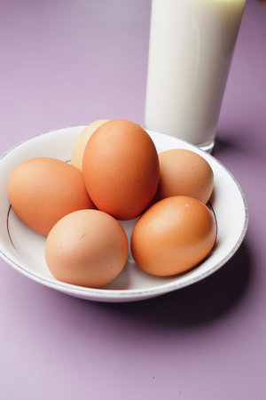 eggs in a bow and a glass of milk on table