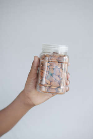 hand holding a jar of almond nuts on whiteの写真素材