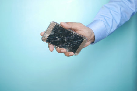 Close up of man hand holding broken smart phone.