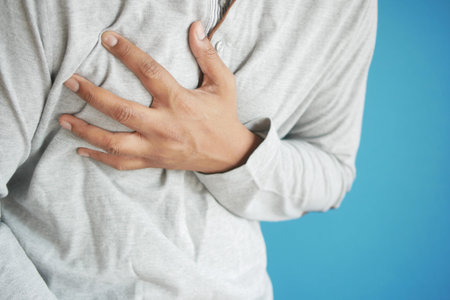 young man suffering pain in heart and holding chest with hand
