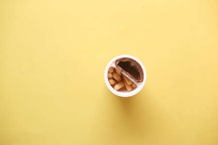 breadstick with chocolate spread cream in a container on yellow backgroundの写真素材