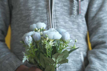 hand holding rose flower against white wallの写真素材