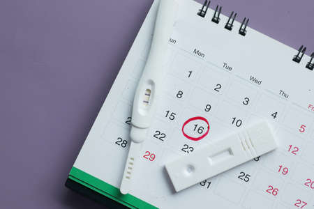 Pregnancy test kit on a calendar close upの写真素材