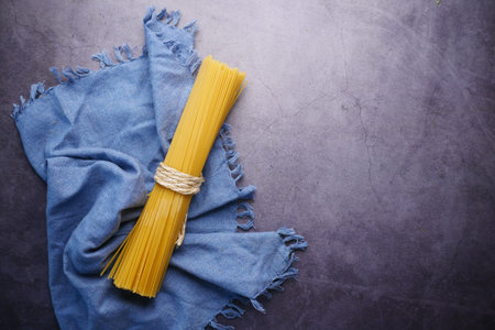 Yellow long spaghetti and a table cloth on black background