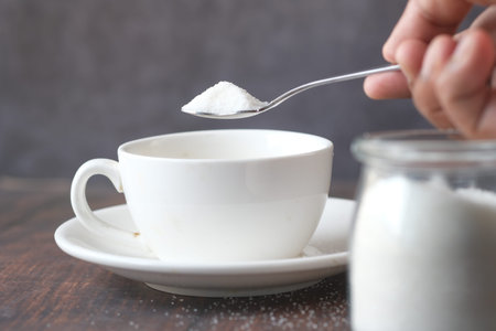 pouting white sugar in a tea cup