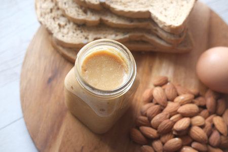 almond butter in a container , egg and bread on tableの写真素材