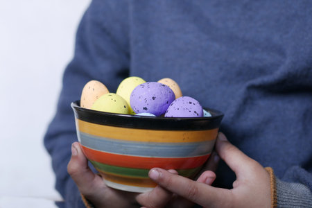 child hand holding a bowl of easter eggs on pink