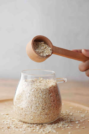 Close up of oats flakes pouring from a wooden spoonの写真素材