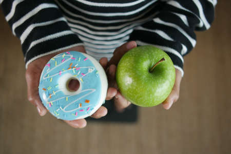 hand holding donuts and apple on hand on weight scale .の写真素材