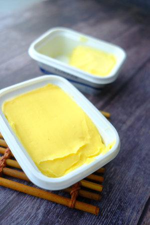 fresh butter in a container with bread on white background