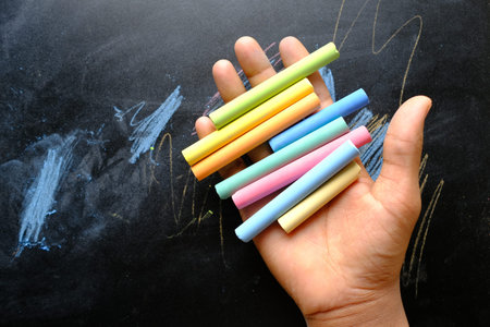 child holding many colorful chalk top view