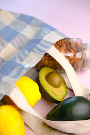 fresh orange fruit and avocado in a shopping bag against black background