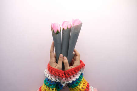 hand holding rose flower on color backgroundの写真素材