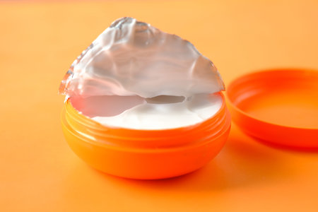 cream in a orange color container on orange background