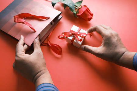 top view of mans hand holding a gift box on tableの写真素材