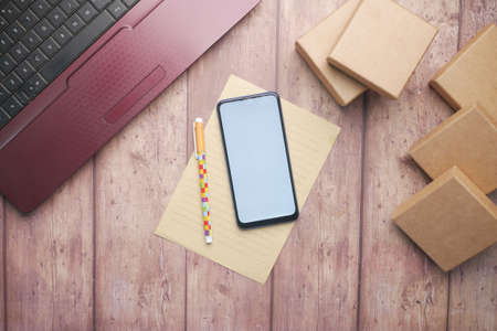 stack of cardboard parcels, smart phone and laptop on tableの写真素材