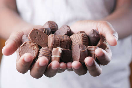 holding many dark candy chocolate close upの写真素材