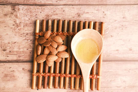 almond oils on a spoon and fresh nuts on tableの写真素材