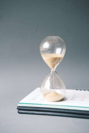 hourglass on a calendar, and flowing through the bulb of sandglassの写真素材