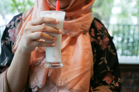 young women drinking banana milk shake at cafeの写真素材