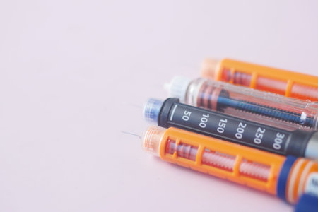 many Insulin pens on light pink background