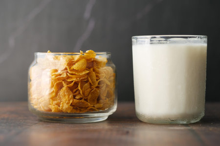 corn flakes and glass of milk on table
