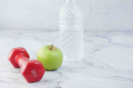 fresh drinking water, apple and a pink color dumbbell on table