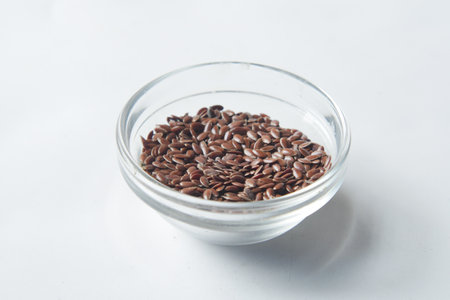 close up of flax seeds on in a glass bowl on whiteの写真素材