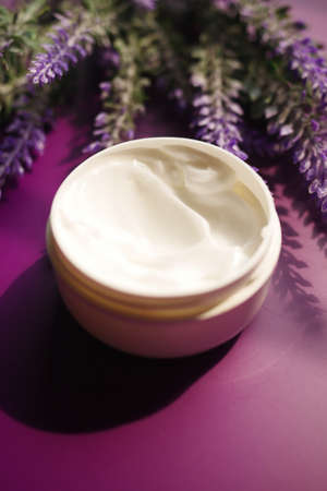 herbal cream cosmetic in a container and lavender flower on purple backgroundの写真素材