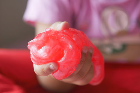 child Hand holding pink color slime