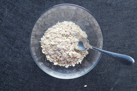 Close up of oats flakes in a glass bowl on black